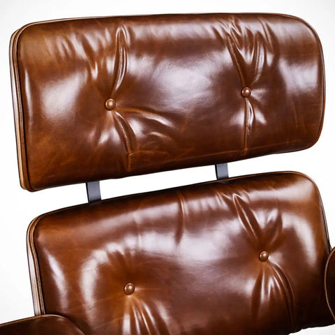 Close-up of a brown leather tufted chair or lounge seat showing the backrest and seat cushions against a plain light background.